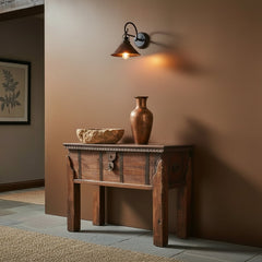Wooden side table with a drawer on a copper wall in a hall