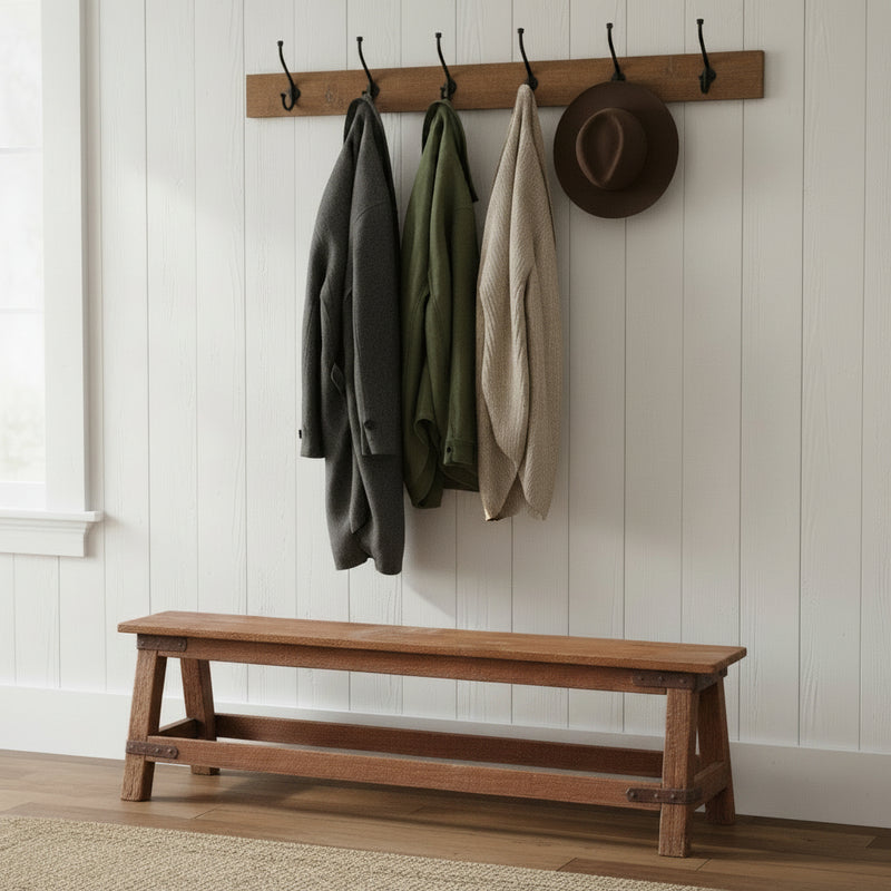 teak bench against a white wall with coat hangers above