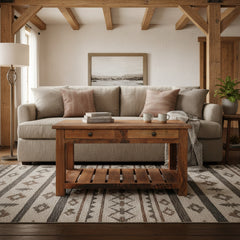 A rustic wooden coffee table with a single drawer, two small round metal knobs, and an open lower shelf, shown in a living room