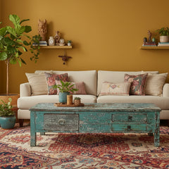 light blue coffee table in an eclectic style living room with a white sofa and a mustard colour wall
