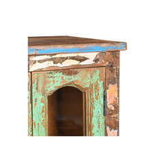 Close-up of a rustic distressed wooden cabinet corner showing peeling turquoise, white, and brown paint on a plain white background.