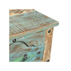 Small side table or bedside locker handcrafted from reclaimed wood with a blue patina. It has one front ornate drawer with rivets, showing a close up view.