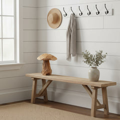 Wooden bench with decorative items against a white wall with hooks.