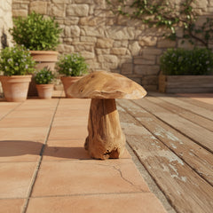 Wooden mushroom-shaped stool on a patio with potted plants and stone wall in the background