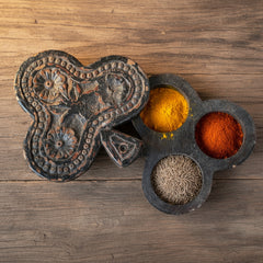 black masala box with spices inside on a wood table