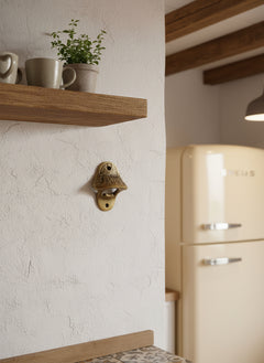 wall mounted bottle opener in brass finish on a white wall in a kitchen