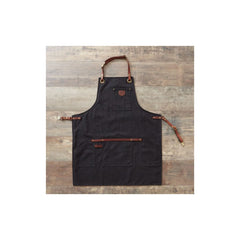 Black apron with brown leather straps on a wooden surface