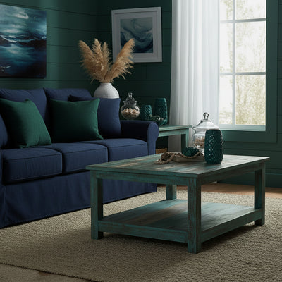 Wooden coffee table with a distressed blue-green finish in a coastal style living room with dark blue sofa