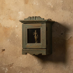 green small wooden box with a glass door on a rustic wall with a statue inside