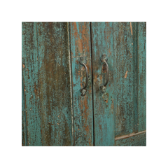A close-up of distressed teal-green wooden cabinet doors with weathered brown wood showing through and dark metal handles, centered on a white background.