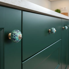 Decorative knob with blue and green pattern on a dark green kitchen drawers and doors