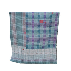 A multicolor plaid and checkered textile blanket or throw is draped over a black metal stand against a white background