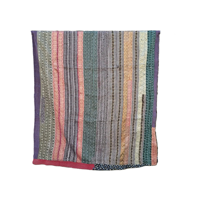 A multicolor striped patchwork quilt with vertical bands of pink, green, purple, and beige patterns, draped over a black metal rolling rack against a white background