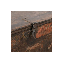 Close-up detail of an antique wooden chest or box with a weathered metal latch and lock on the front, showing distressed brown wood and faded orange-red paint.