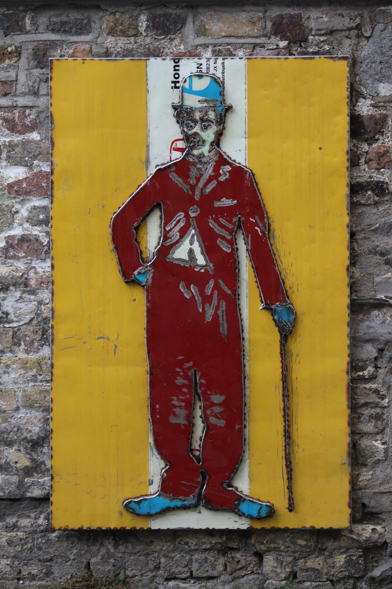 Charlie Chaplin on Yellow Background with Red Body Front View Metal Art Work Outside