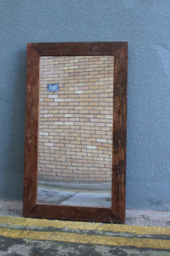 Natural Wood mirror marine leaning against outside wall 