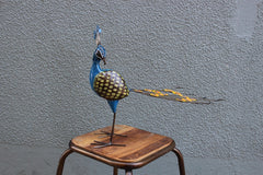 Recycled metal sculpture of a peacock with open tail handpainted in blue, orange and yellow.