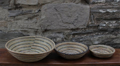 handcrafted round baskets. Three sizes made with recycled plastic and straw. set of three size comparison. Black, grey, and white.