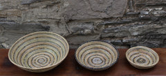 handcrafted round baskets. Three sizes made with recycled plastic and straw. Set of three size comparison. Black, grey, and white.